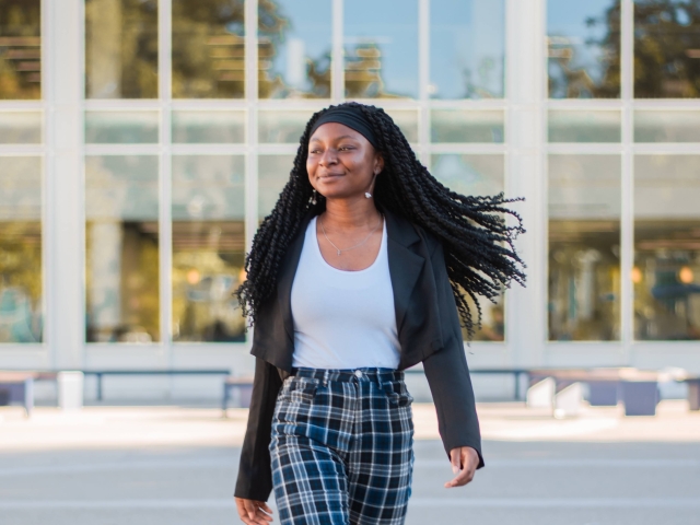UC Davis Student Xaviera Azodoh walking outdoors with her hair swinging and one leg in front of the other